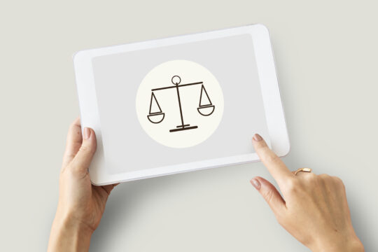 Dłonie z tabletm na ekranie którego widać wagę szalkową