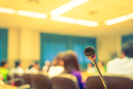 Mikrofon na rozmytym żółtym tle sali konferencyjnej